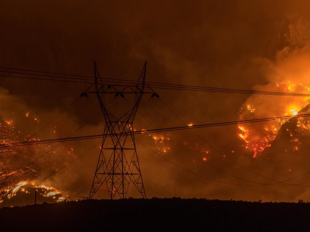 Wildfires in California burn behind transmission lines. 