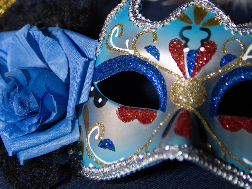 Masquerade mask sitting next to rose