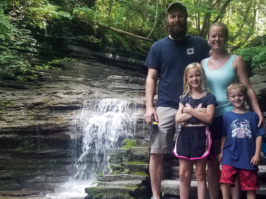 Family posing in front of a waterfall