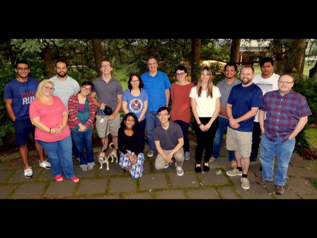 A diverse group of people stand and smile for a photographer.