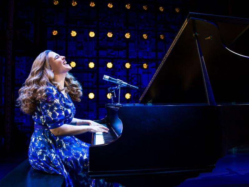 A woman throws her head back and sings while playing at a grand piano.