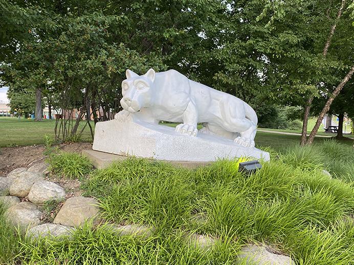 The Nittany Lion shrine sits among greenery in front of the campus quad