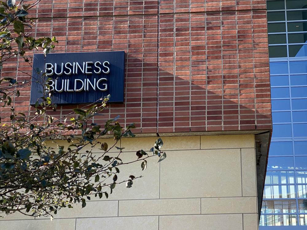 The sign for the Business Building is on a brick wall.