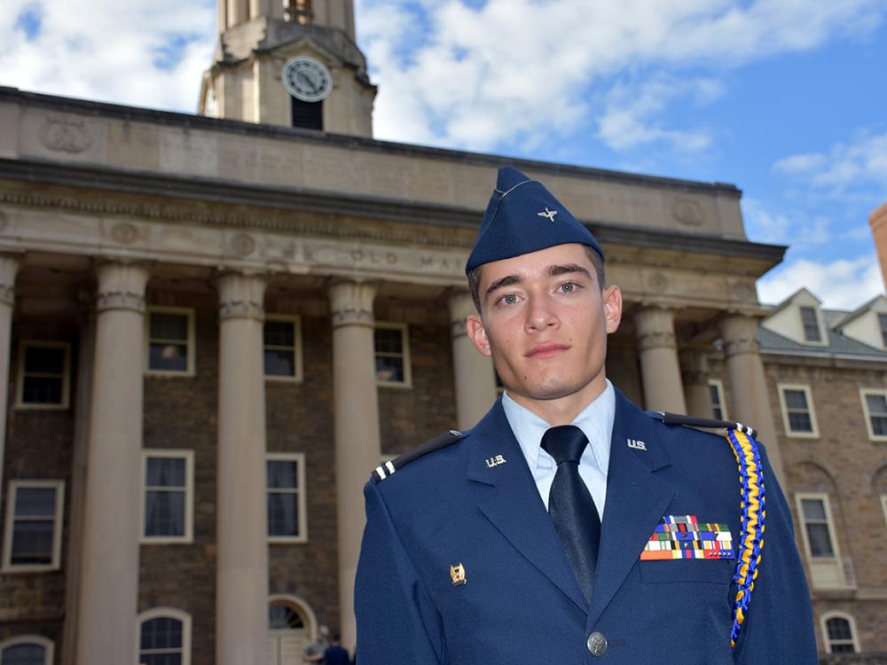 Cadet Josh Maldonado-Santiago stands in uniform in front of Old Main