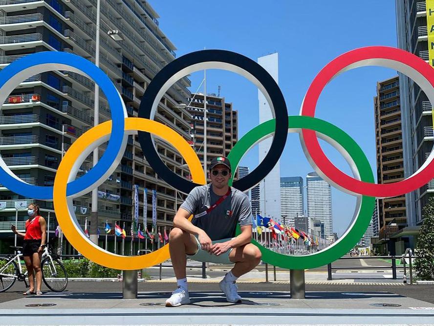 Gabe Castaño standing in front of the Olympic rings