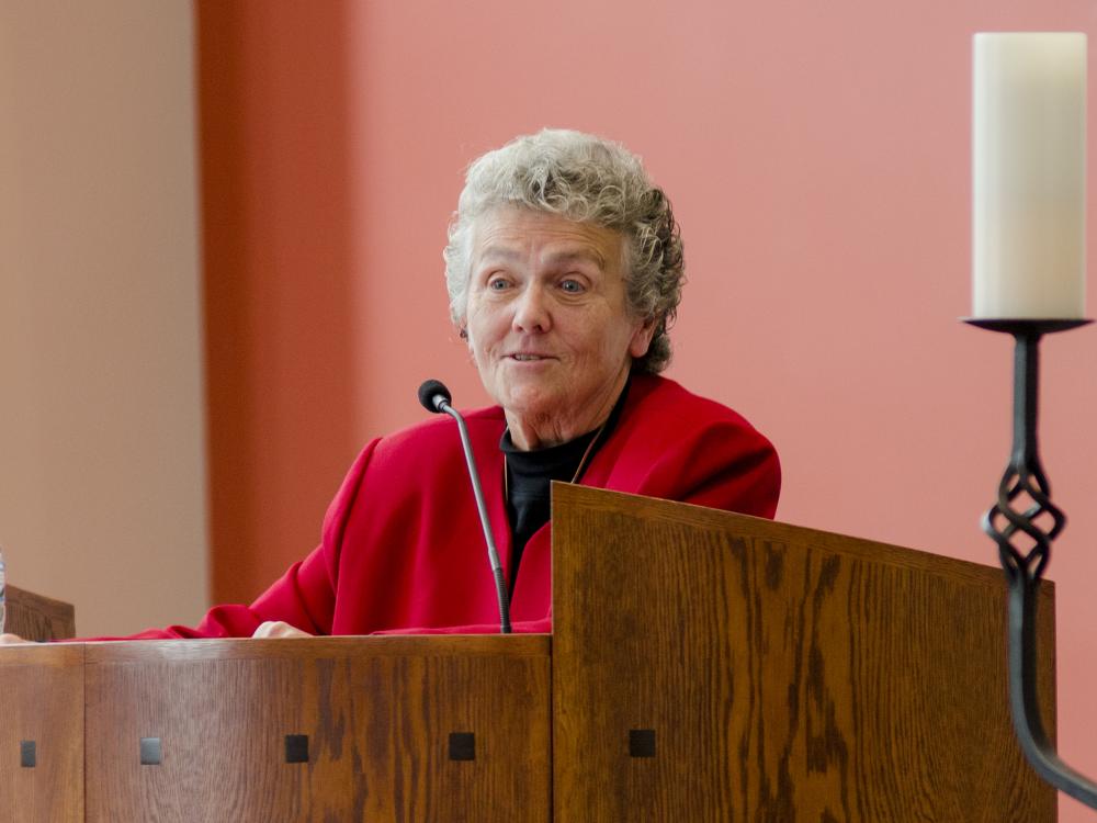 Sister Joan Chittister standing at a podium speaking to an audience