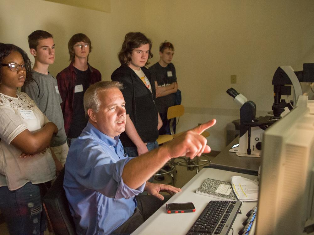 Jerry Magraw, senior technician in Penn State Behrend's School of Science, instructs students on how to use the confocal microscope during the college's High School Academy. 