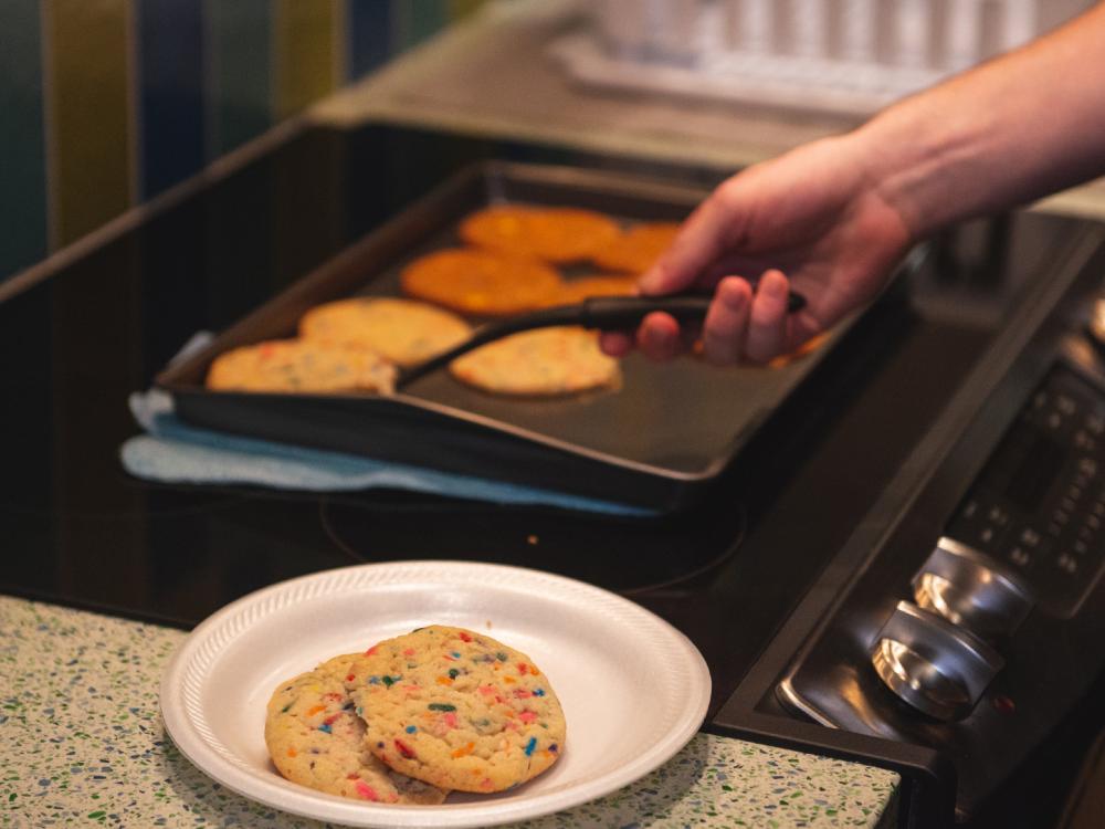 Student removing cookies from a baking sheet