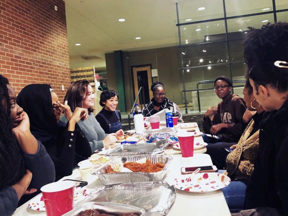 Students sit around a table eating and talking.