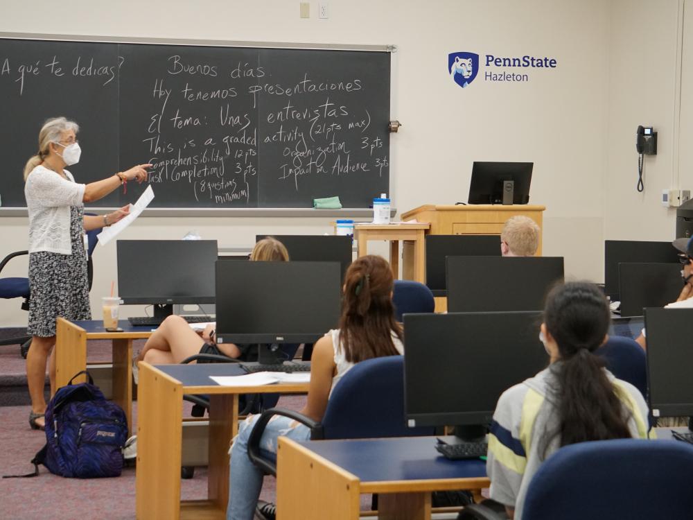 Teacher pointing to a student as others look on inside a classroom