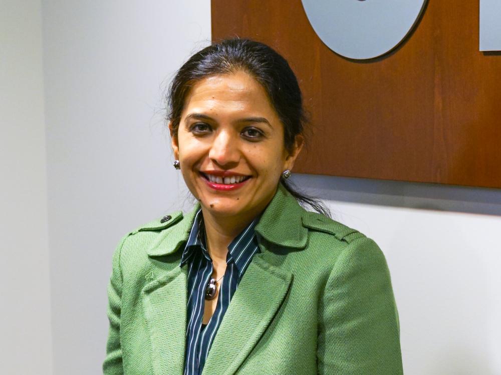 Woman smiles for camera in green jacket.