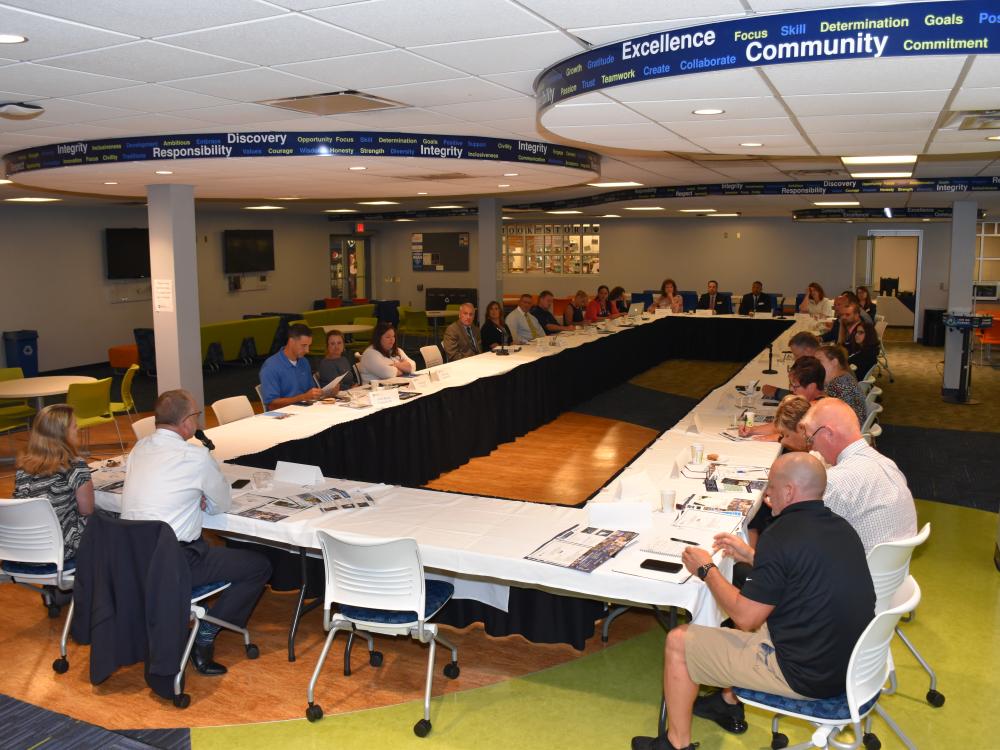 A forum of high school administrators and Penn State Fayette staff are seated around a large table in the Student Center.