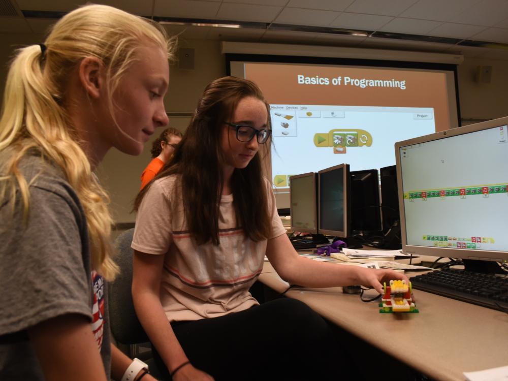 Sydney Rotko, at left, and Sammy Fellows, both students in the General McLane School District, work on programming the alligator they created as part of GE Girls @ Penn State Behrend.