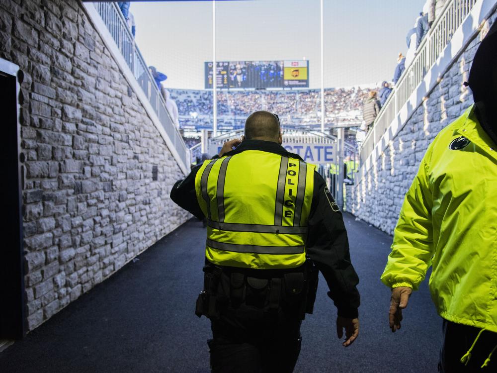 A Penn State Police officer stands in the tunnel at Beaver stadium looking out onto the football field.