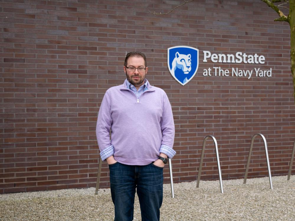 Todd Krout standing in front of the Penn State at the Navy Yard logo on Build 7R at the Navy Yard