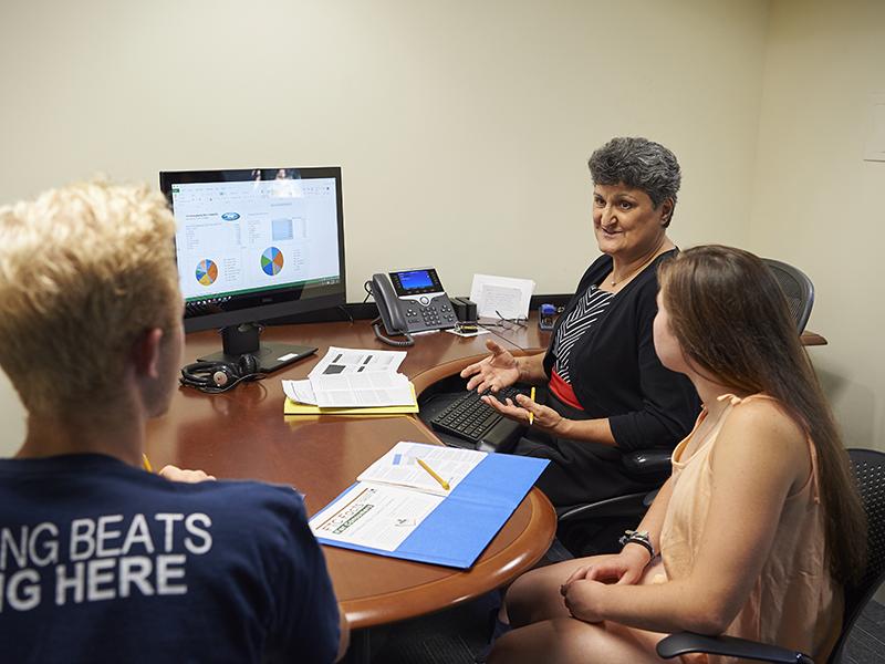 Daad Rizk, director of Penn State's Financial Literacy and Wellness Center, assists students from her office in Grange Building at University Park. 