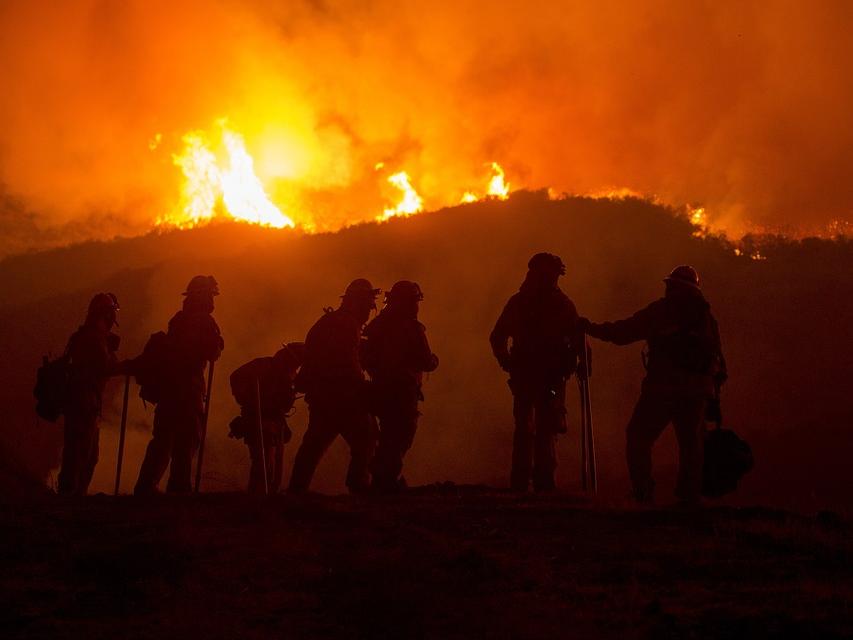 silhouette of firefighters in front of wildfire