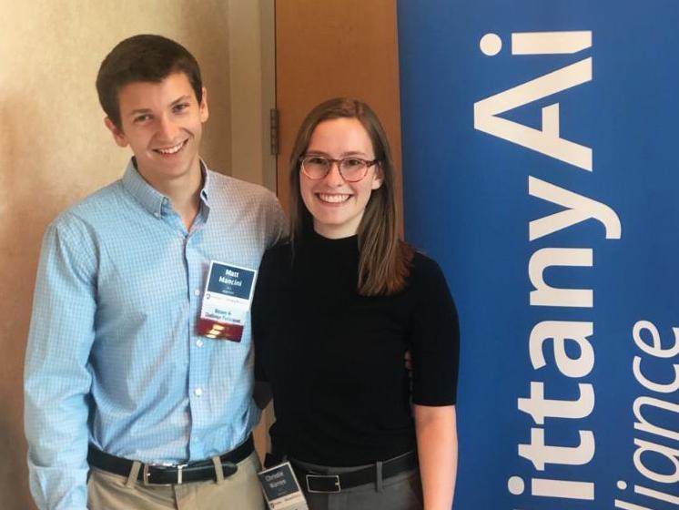 Matthew Mancini, left, and Christie Warren pose next to the Nittany AI Challenge banner.