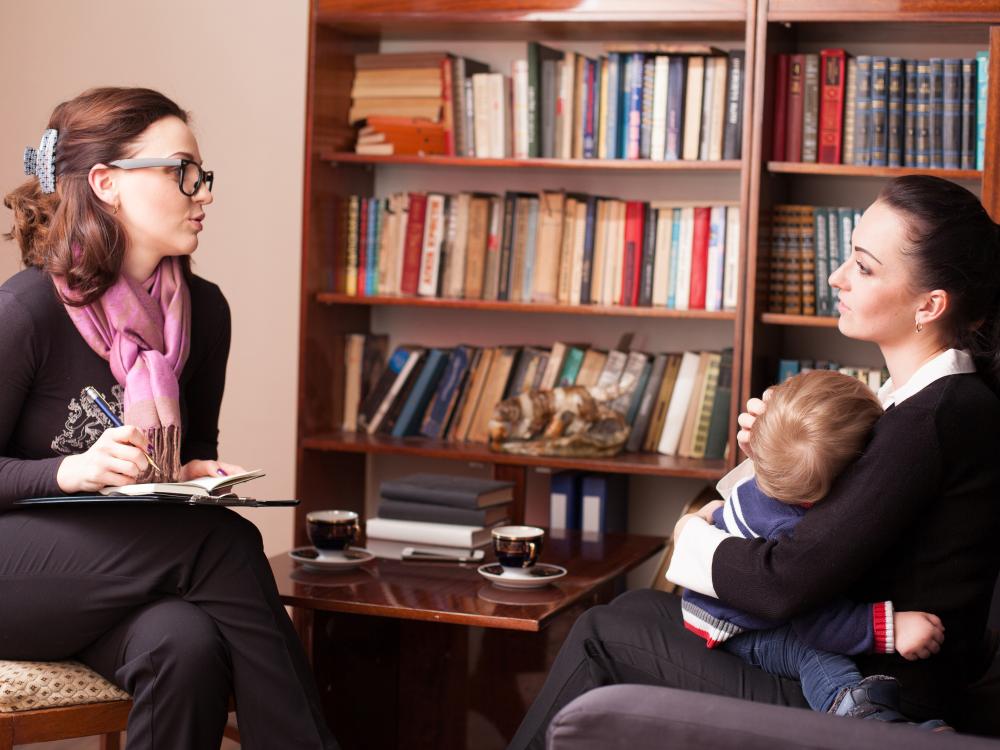 Woman talking to woman holding baby in office