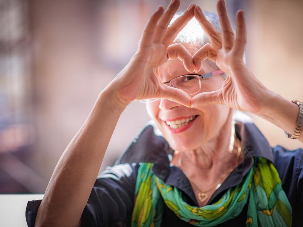 Older woman making a heart shape with her hands