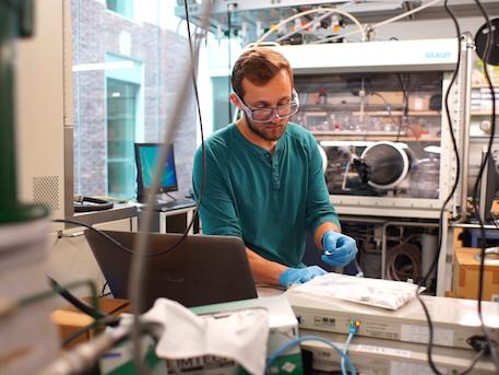 Bearded man wearing safety glasses in laboratory conducts an experiment in a laboratory.