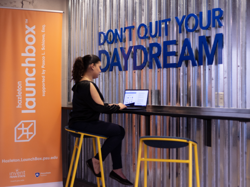 An individual is working at the Hazleton LaunchBox under a "Don't Quit Your Daydream" sign.