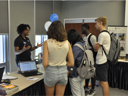 Shidika Goode, Resource Specialist, explains career resources to students during Career Services Open House