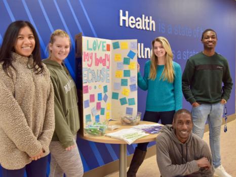 A diverse group of HealthWorks peer mentors pose during a community outreach event