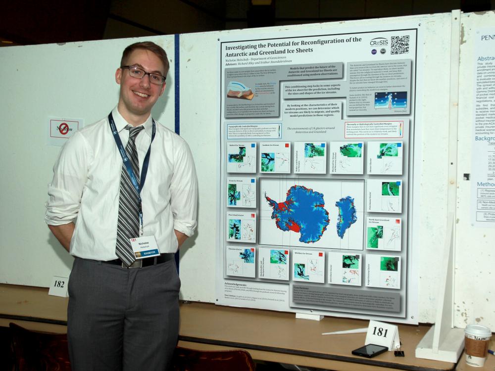 student standing next to research poster