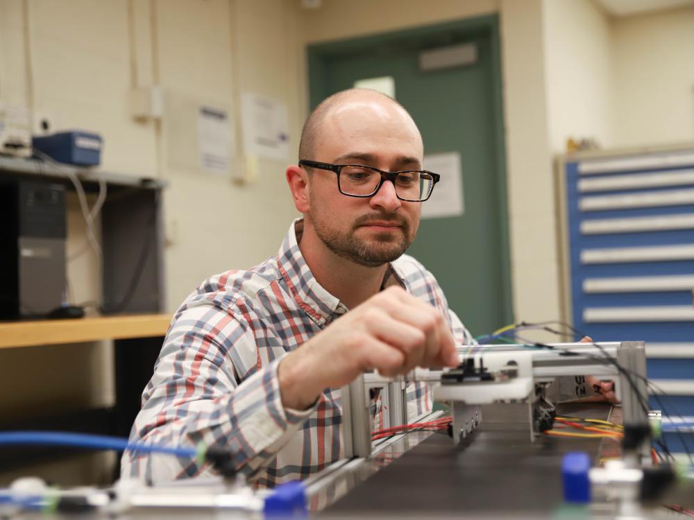 Joseph Cuiffi wiring conveyor belt in lab