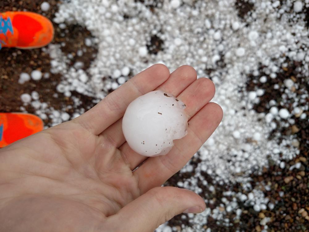 A student holds a piece of hail the size of a golf ball