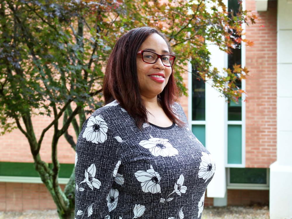 woman wearing glasses smiling in front of a tree 