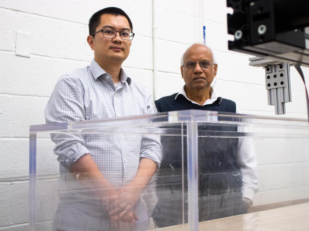 Two men stand in front of a tank of water in a research laboratory. 