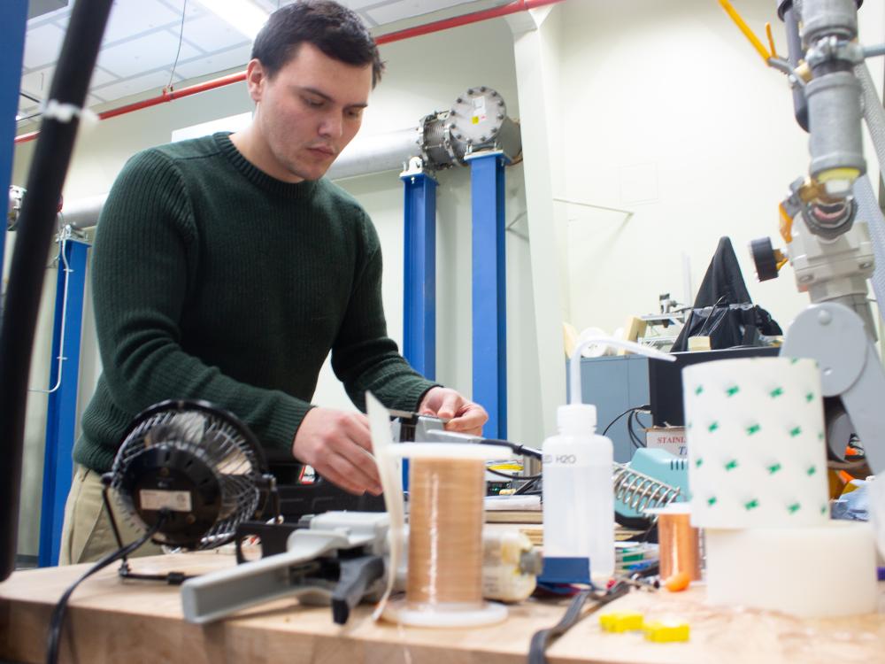 A Caucasian man works with gas turbine components in a lab.