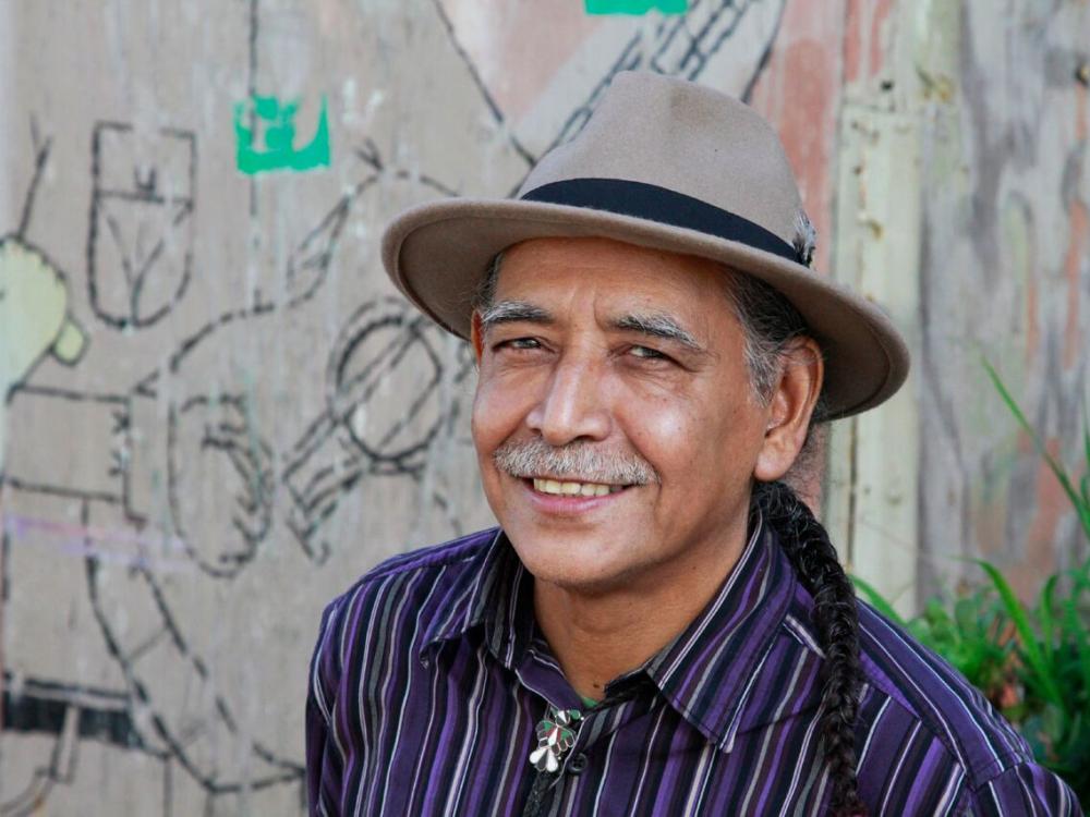 photo portrait of Jorge Argueta, man with mustache wearing hat and striped shirt