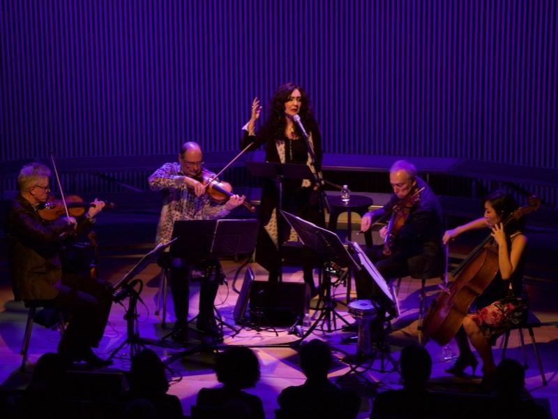 A woman stands in the center of a string quartet and sings.