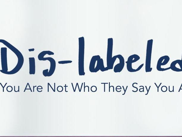 Person holding sign that says: Dis-labeled: You are not who they say you are