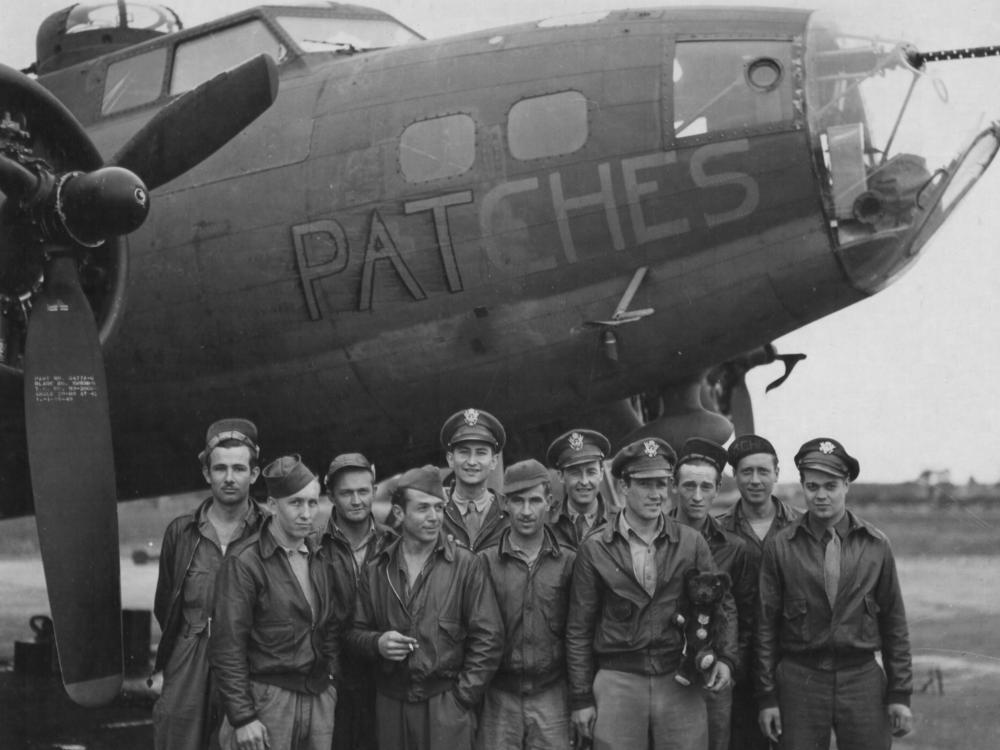 WWII flight crew stands in front of their plane in England 