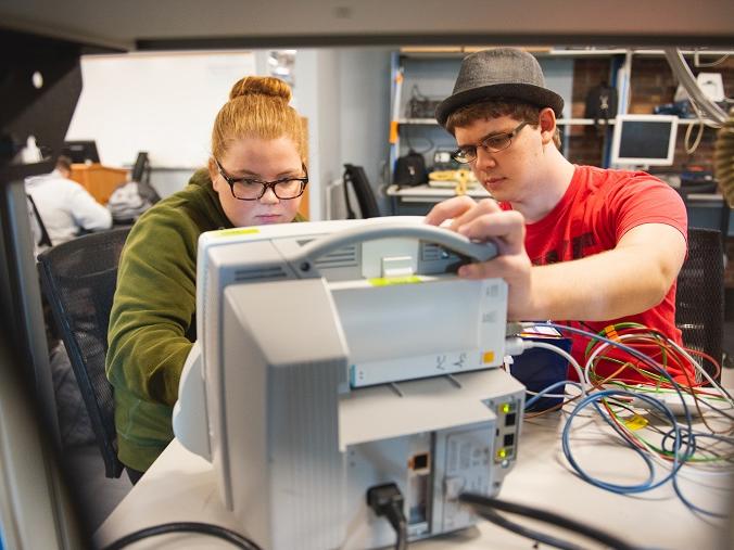 Two students work on hospital equipment in lab