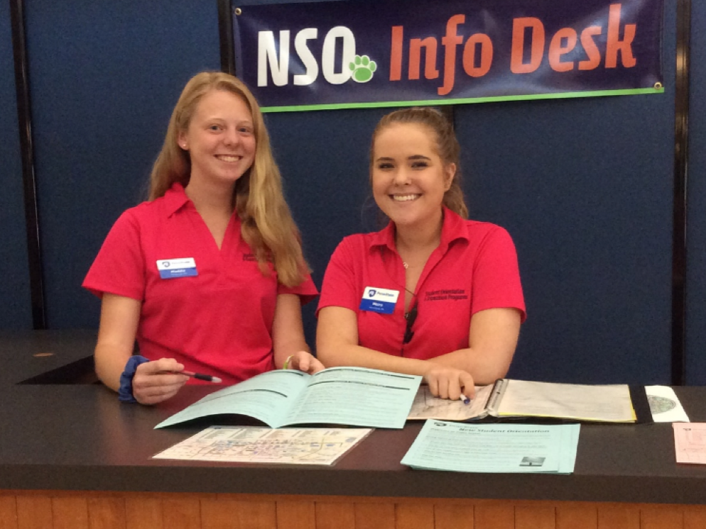 Two members of the OTeam stand at the NSO Information Desk ready to help students and families