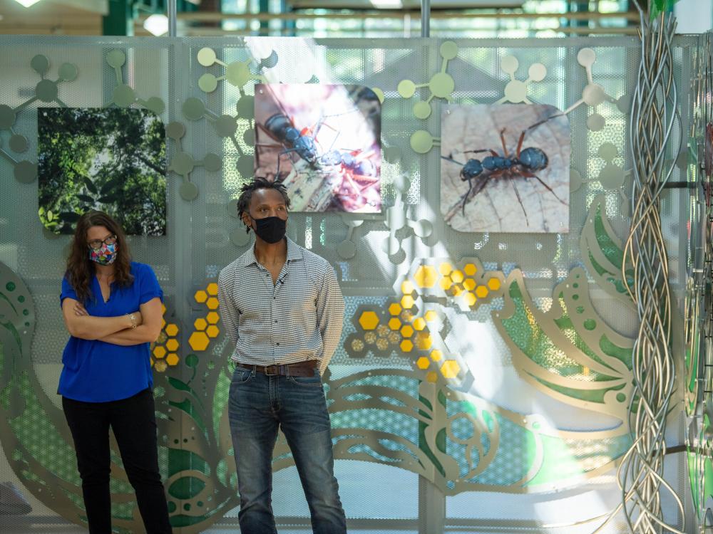 A woman and a man stand in front of an interactive art sculpture at Penn State Behrend.