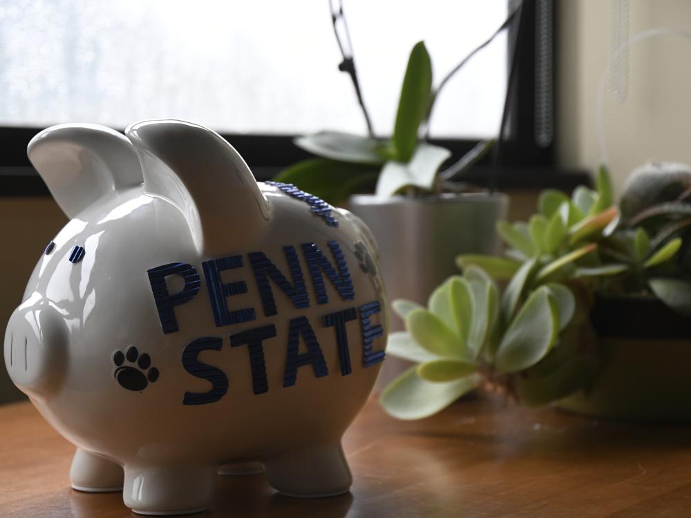 A Penn State piggy bank on a desk with succulent plants 