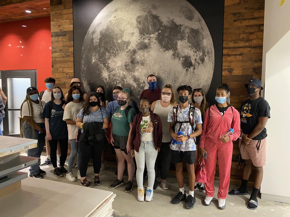 Ri at Penn State Summer Program students in front of a large photo of the Moon.