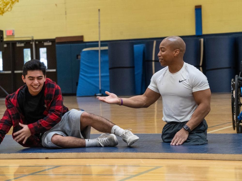 Rohan Murphy presenting at high school gym with student