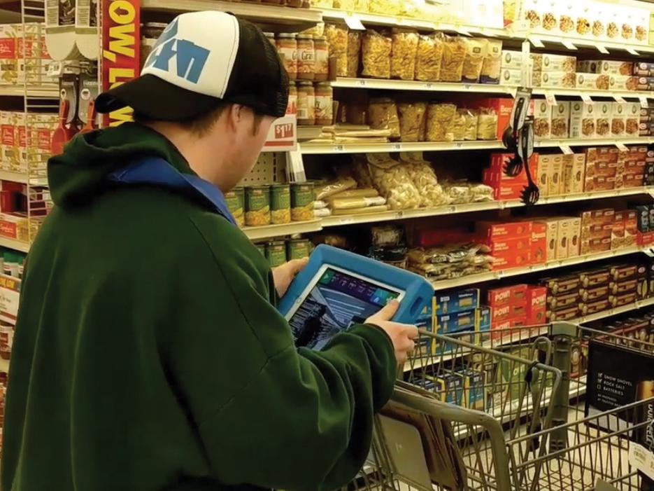 An individual uses a Video Visual Scene Displays app developed by the Rehabilitation Engineering Research Center on Augmentative and Alternative Communication to aid him while grocery shopping.