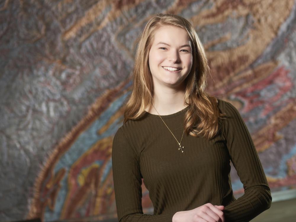 Sara Maholland standing in front of a topographical map of Pennsylvania