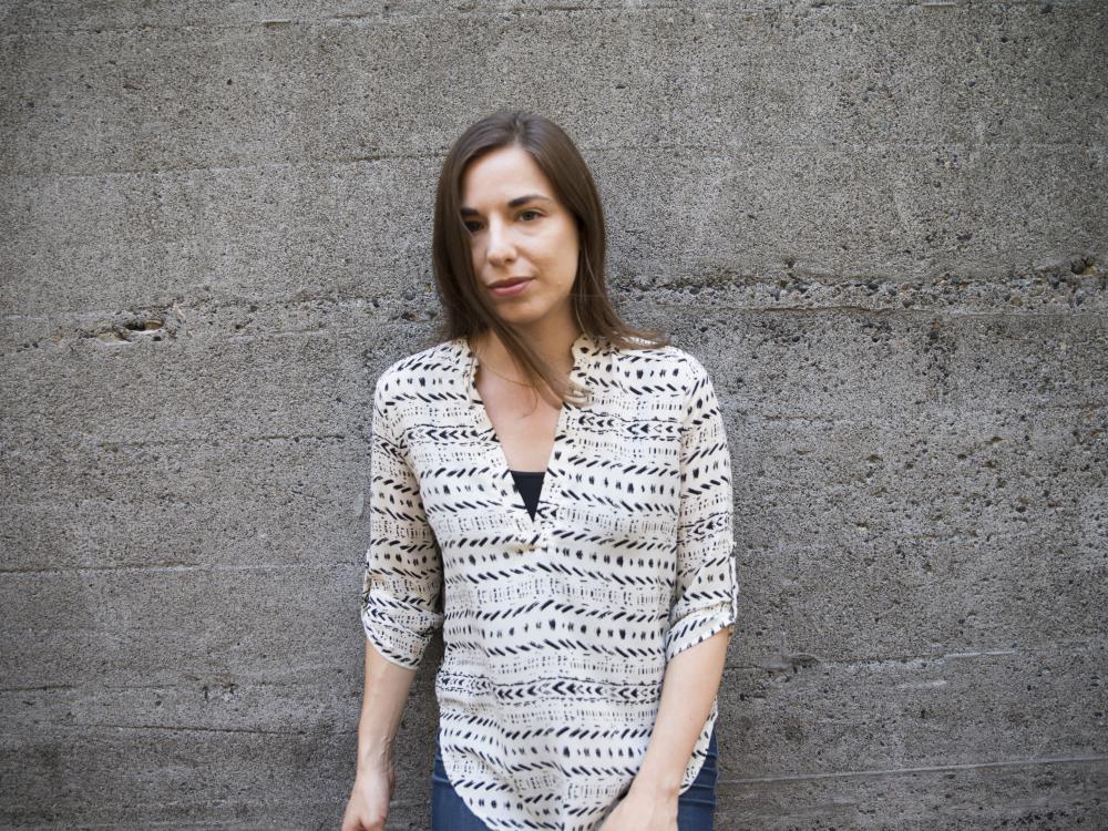 horizontal portrait of Sarah Glidden standing, leaning against concrete wall