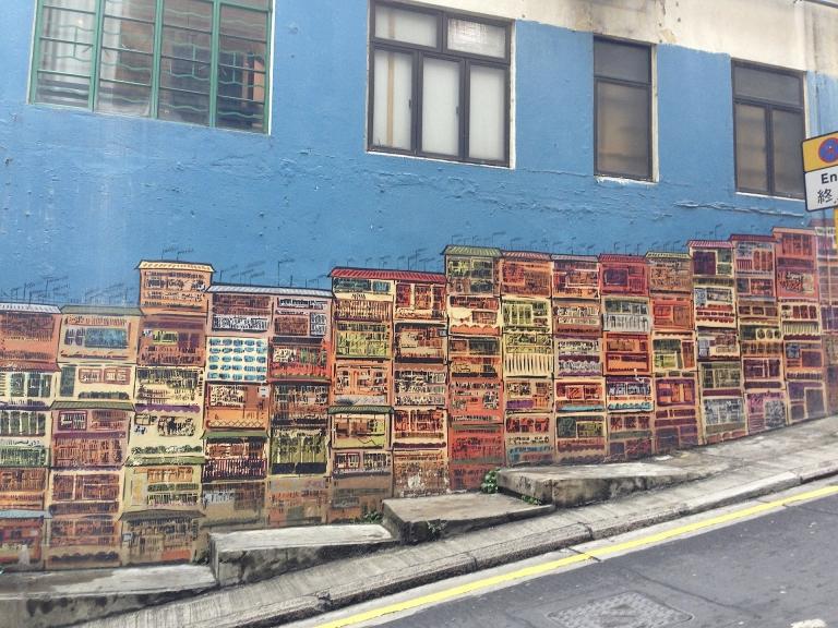Tall, colorful buildings are painted on the side of a building in Hong Kong