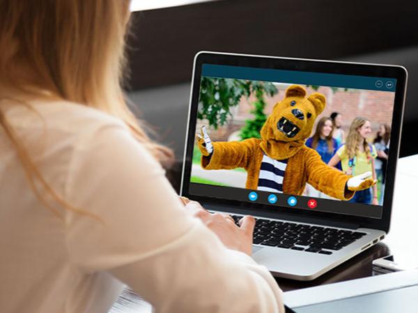 A woman chatting with the Nittany Lion on her laptop