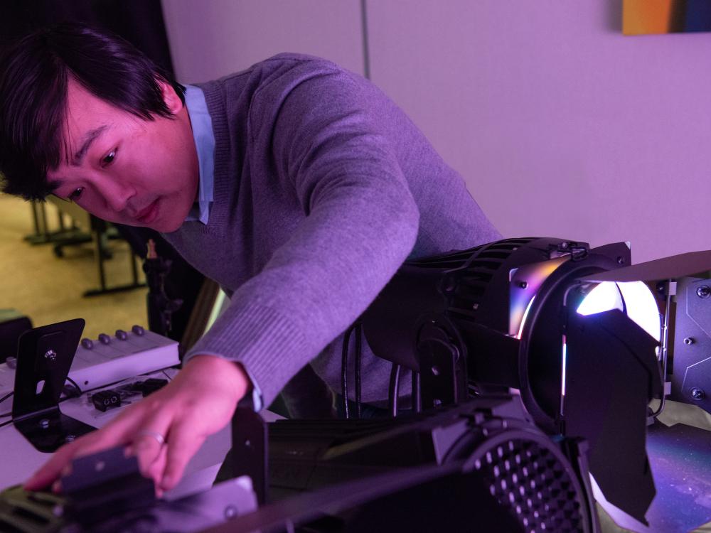 Asian man adjusts a light 